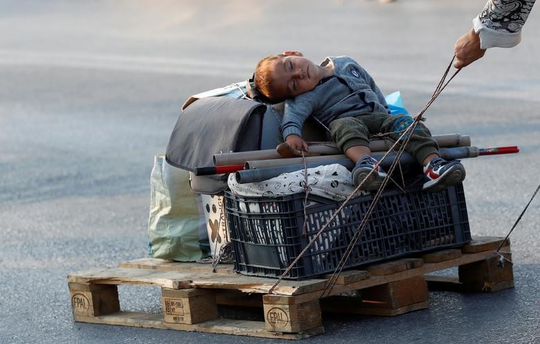 A woman pulls a baby on a pallet as they prepare to move to a new temporary camp for migrants and refugees, on the island of Lesbos, Greece. REUTERS/Yara Nardi  